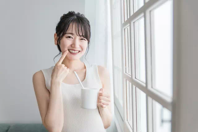 歯を指さし笑顔の女性の画像